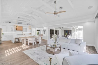 Living room with sink, light hardwood / wood-style flooring, ceiling fan with notable chandelier, and lofted ceiling | Image 3