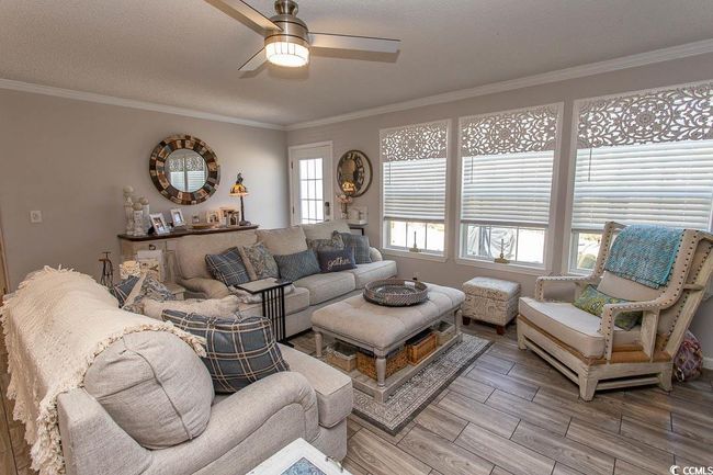 Living room with ornamental molding, light wood finished floors, and a ceiling fan | Image 19