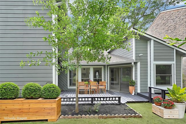 This beautifully updated backyard offers a charming blend of greenery and functionality with a freshly painted wood deck, newly landscaped garden beds, and a young shade tree adding curb appeal and comfort. Ideal for relaxing or entertaining, this private outdoor space is accessible from multiple sliding doors and showcases the home's striking architectural lines. | Image 46