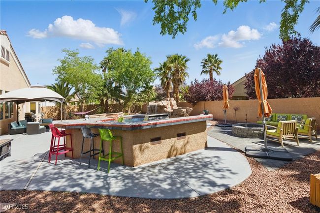 View of patio / terrace featuring a fenced backyard, outdoor dry bar, an outdoor living space with a fire pit, and a gazebo | Image 35