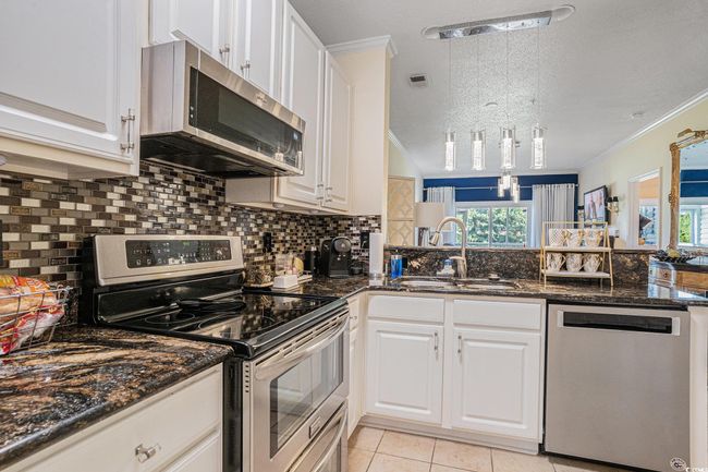 Kitchen featuring stainless steel appliances, healthy amount of natural light, backsplash, crown molding, and a textured ceiling | Image 9