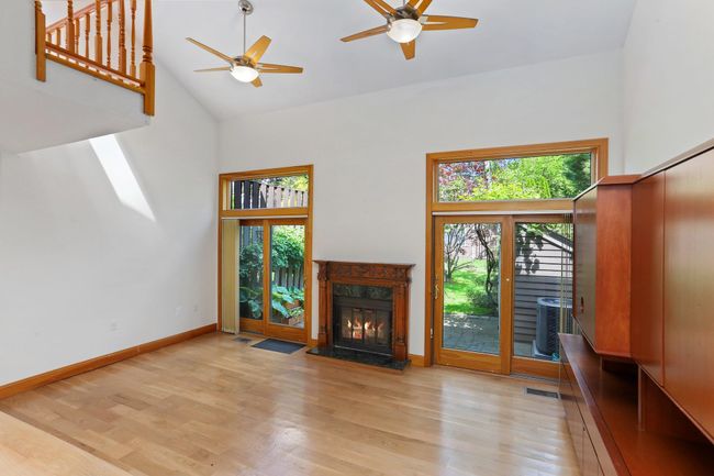 Unfurnished living room with high vaulted ceiling, plenty of natural light, ceiling fan, wood finished floors, and a high end fireplace | Image 13