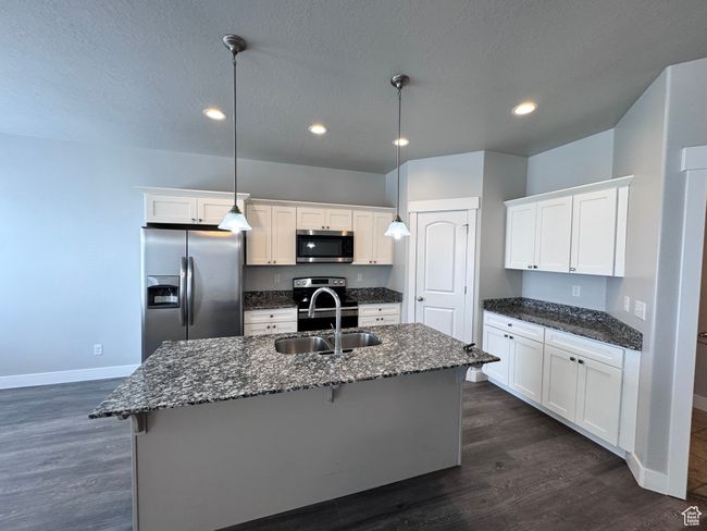 Kitchen with recessed lighting, appliances with stainless steel finishes, white cabinets, a sink, and baseboards | Image 8