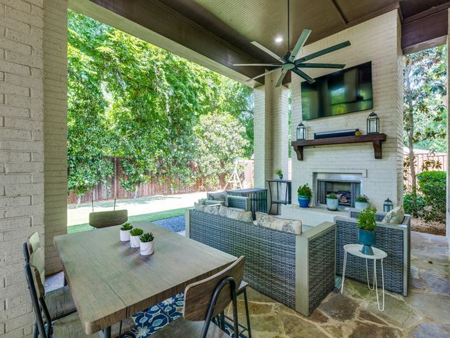 View of patio / terrace featuring fence, ceiling fan, an outdoor living space with a fireplace, outdoor dining space, and central AC | Image 18