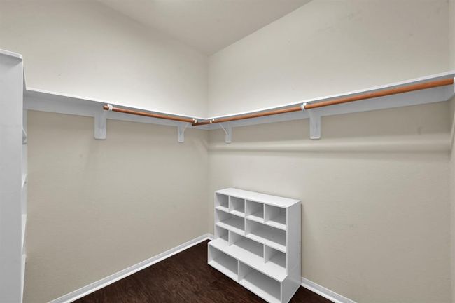 This room features a single window with blinds, neutral walls, and wood flooring. It's equipped with a wall mount for a TV, making it ideal for a cozy media room or office space. | Image 21