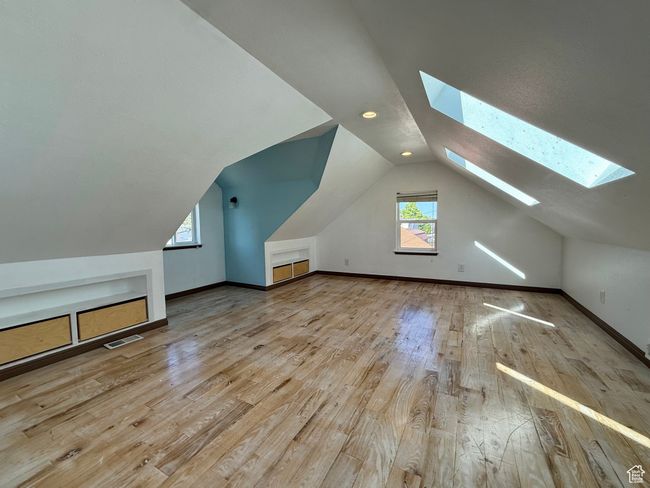 Bonus room with a skylight, hardwood / wood-style flooring, lofted ceiling, and baseboards | Image 26