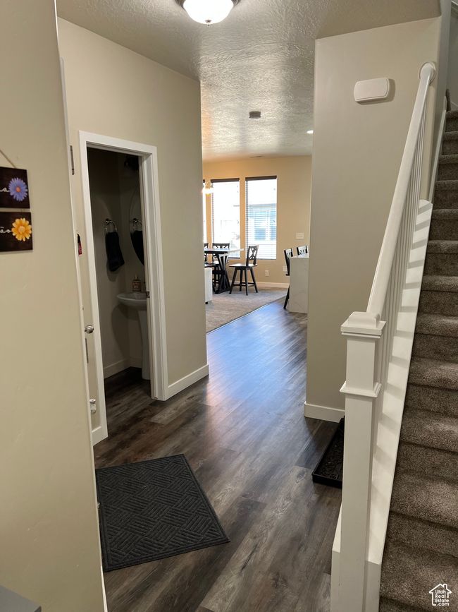 Corridor featuring baseboards, stairway, a textured ceiling, and dark wood-type flooring | Image 13
