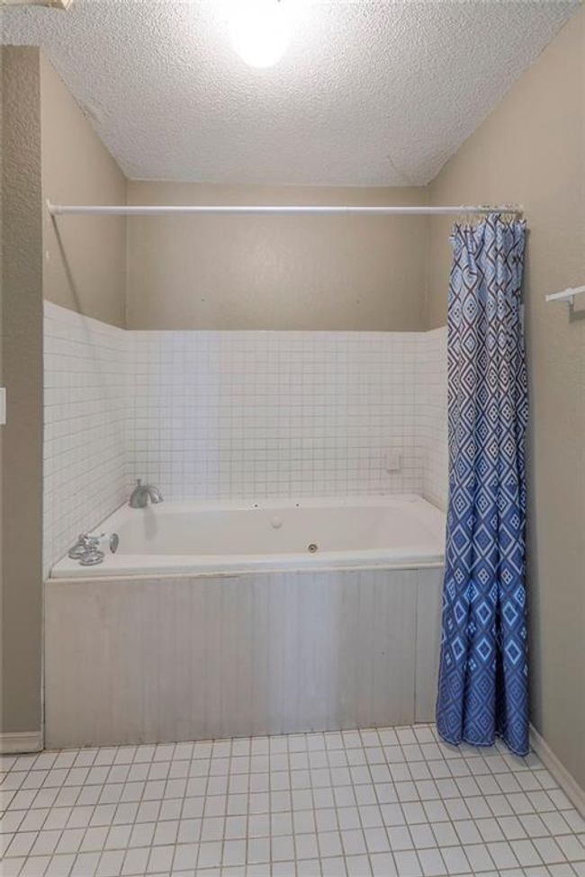 Full bathroom featuring shower / bath combo with shower curtain, tile patterned flooring, and a textured ceiling | Image 29
