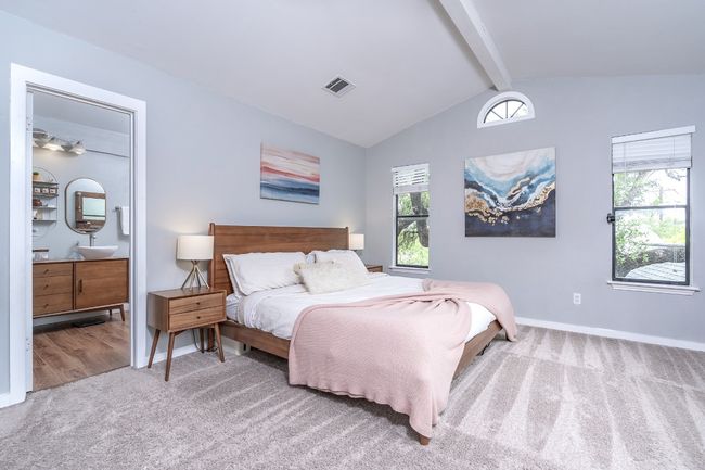 Large bedroom with lofted ceiling with beams, ensuite full bathroom, baseboards, and carpet. | Image 18