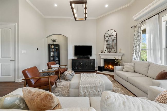 Living room with recessed lighting, ornamental molding, dark wood-style flooring, and a warm lit fireplace | Image 7