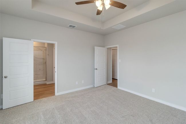 Unfurnished bedroom with baseboards, visible vents, a tray ceiling, and carpet flooring | Image 30
