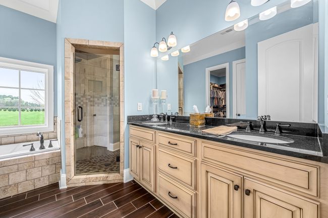 The primary bathroom is a luxurious space designed for relaxation. With soaring ceilings, it feels open and airy. Offers a tile floor, walk-in shower, double sink vanity with granite countertops, and a garden tub completes this serene retreat. | Image 55