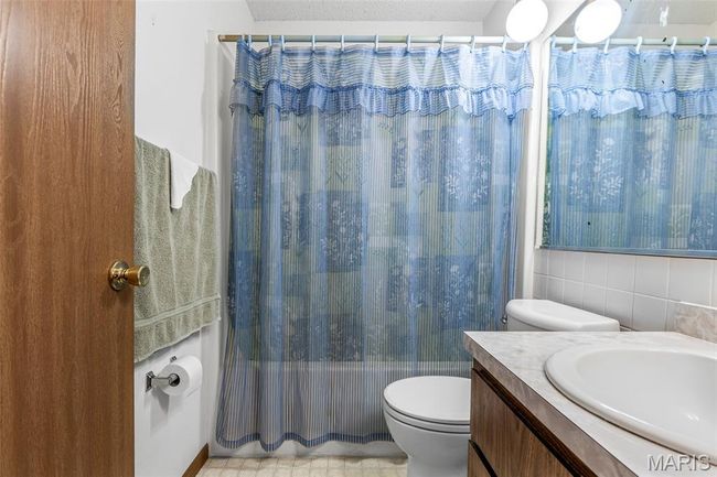 Full bath featuring toilet, shower / bath combo with shower curtain, vanity, and tasteful backsplash | Image 31