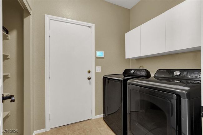 Washroom featuring washing machine and clothes dryer, cabinet space, and light tile patterned flooring | Image 20