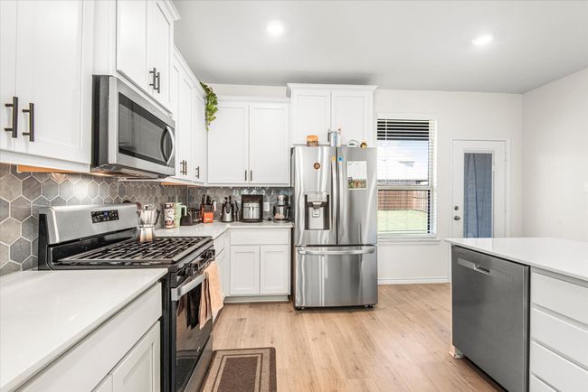 Kitchen featuring backsplash, light wood-style flooring, stainless steel appliances, and light countertops | Image 13