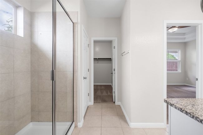 Bathroom with a shower stall, a walk in closet, vanity, and tile patterned floors | Image 24