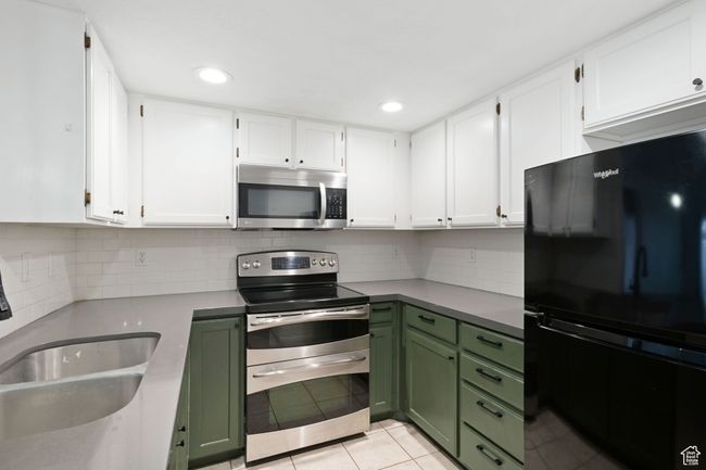 Kitchen with white cabinetry, appliances with stainless steel finishes, and green cabinetry | Image 8