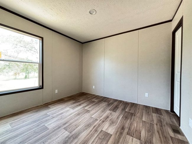 Unfurnished room with a textured ceiling, light wood look-style floors, a decorative wall, plenty of natural light, and ornamental molding | Image 18