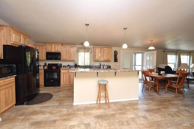 Kitchen featuring black appliances, light brown cabinets, a breakfast bar, and healthy amount of natural light | Image 7