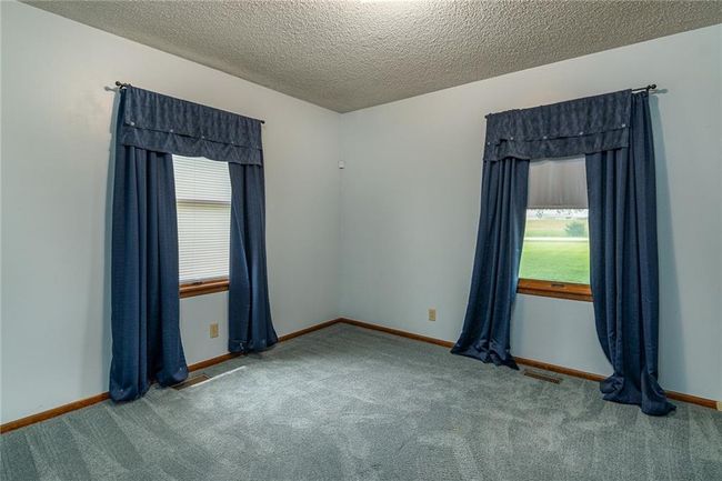 Unfurnished bedroom with multiple windows, light colored carpet, and a textured ceiling | Image 17