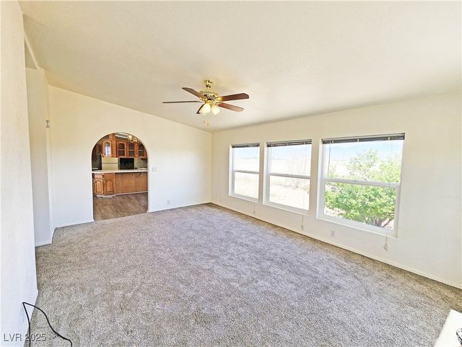 Unfurnished room with arched walkways, ceiling fan, carpet, and baseboards | Image 13