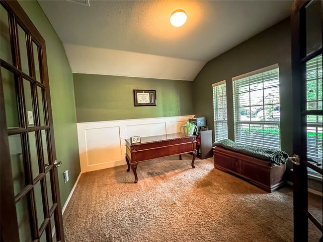 Carpeted home office with a decorative wall, french doors, a wainscoted wall, and vaulted ceiling | Image 20