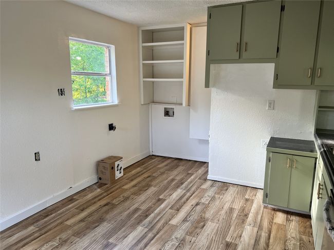 Laundry area featuring light wood finished floors, baseboards, a textured ceiling, and washer hookup | Image 4