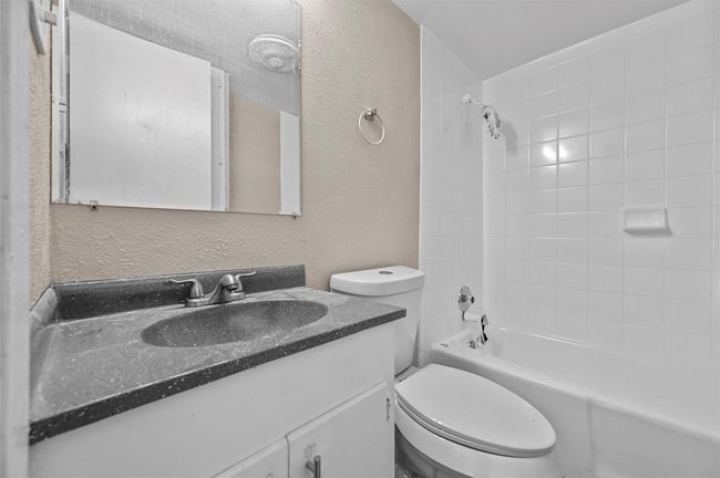 Full bath with a textured wall, vanity, and bathtub / shower combination | Image 14