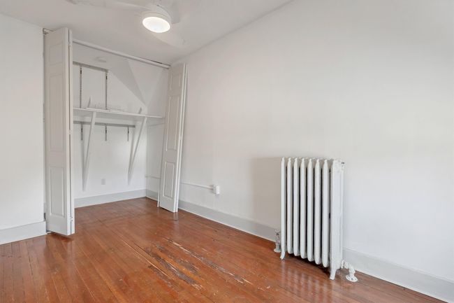 Unfurnished bedroom featuring radiator, wood-type flooring, and baseboards | Image 40