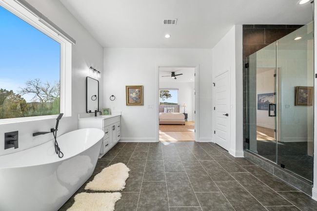 The primary ensuite luxury bath on the main level is a true retreat, offering a double vanity, walk-in closet, spa-like bath with a designer rain shower, and a freestanding tub. | Image 20