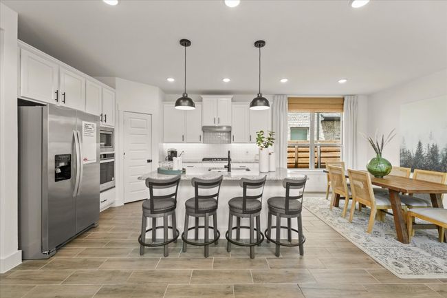 Kitchen featuring appliances with stainless steel finishes, white cabinetry, decorative backsplash, recessed lighting, and a breakfast bar | Image 19