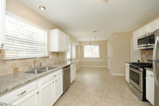 Beautiful backsplash and window over the sink. Kitchen opens to breakfast room. | Image 12