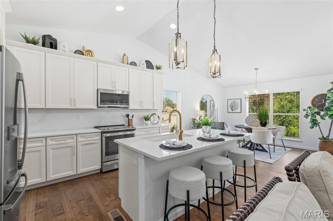 Kitchen with appliances with stainless steel finishes, a sink, a chandelier, light countertops, and white cabinetry | Image 13