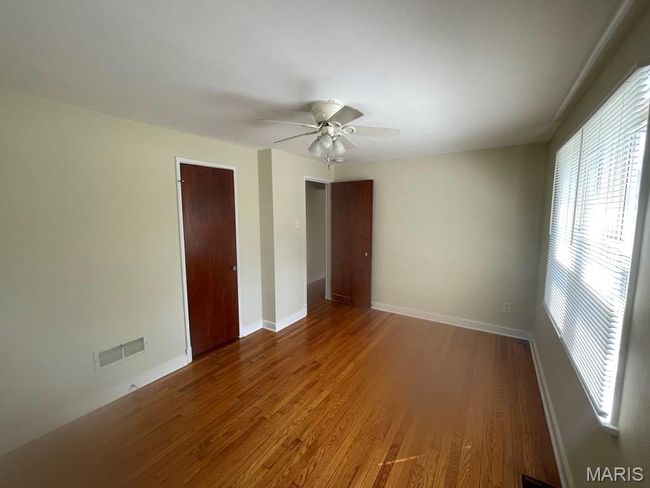 Empty room with wood finished floors, visible vents, baseboards, and ceiling fan | Image 15