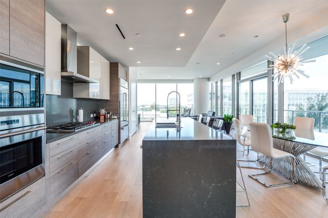 Kitchen featuring modern cabinets, light wood-style flooring, built in appliances, a center island with sink, and a chandelier | Image 11