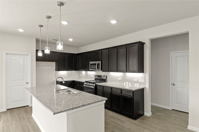 Kitchen featuring appliances with stainless steel finishes, light wood finished floors, light stone counters, and recessed lighting | Image 18