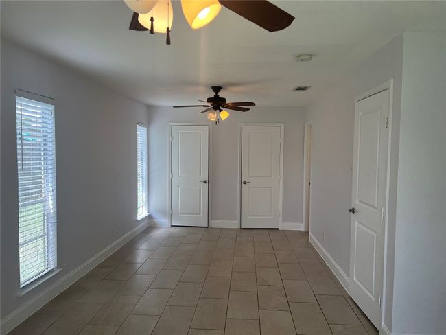 Unfurnished room with healthy amount of natural light, ceiling fan, and light tile patterned floors | Image 14