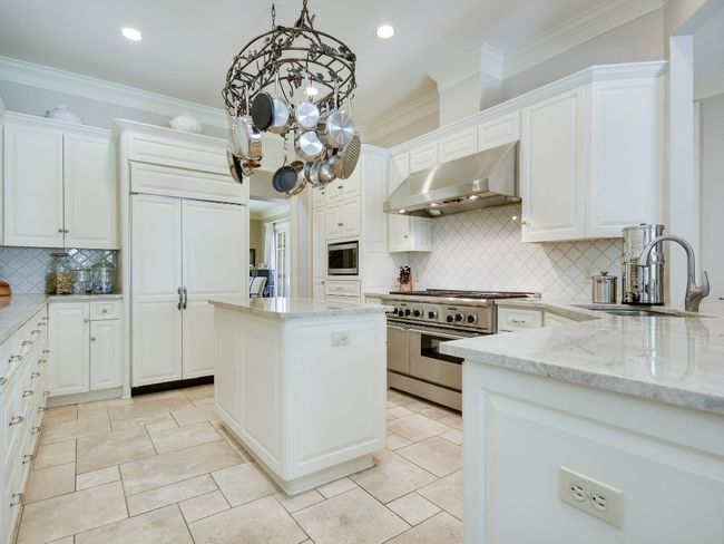 Kitchen featuring under cabinet range hood, appliances with stainless steel finishes, a sink, tasteful backsplash, and light stone countertops | Image 8