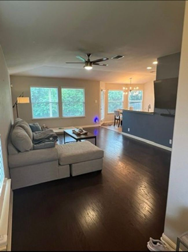Living area with a chandelier, dark wood-style floors, and healthy amount of natural light | Image 4