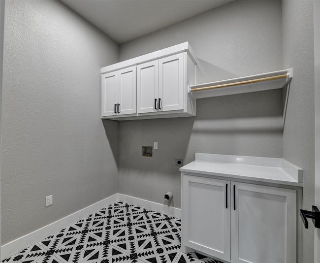 Laundry area featuring tile patterned floors, hookup for an electric dryer, cabinets, and hookup for a washing machine | Image 31