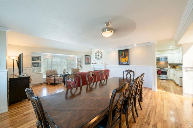 Dining area featuring a decorative wall, light wood-style floors, crown molding, and a wainscoted wall | Image 17