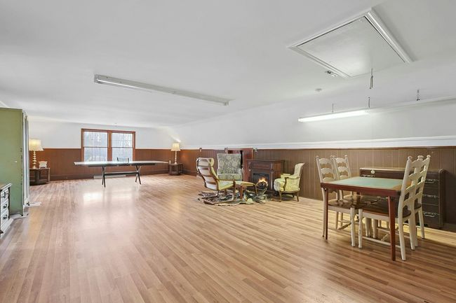 Recreation room with attic access, light wood-type flooring, a warm lit fireplace, and wainscoting | Image 27