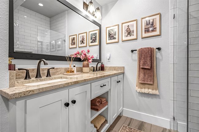Full bath with wood finished floors, double vanity, baseboards, and tiled shower | Image 16