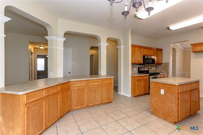 Kitchen with archways large bar area, wooden cabinets, island, tile floors and breakfast area. | Image 12