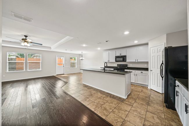 Kitchen with black appliances, open floor plan, dark countertops, ceiling fan, and recessed lighting | Image 12