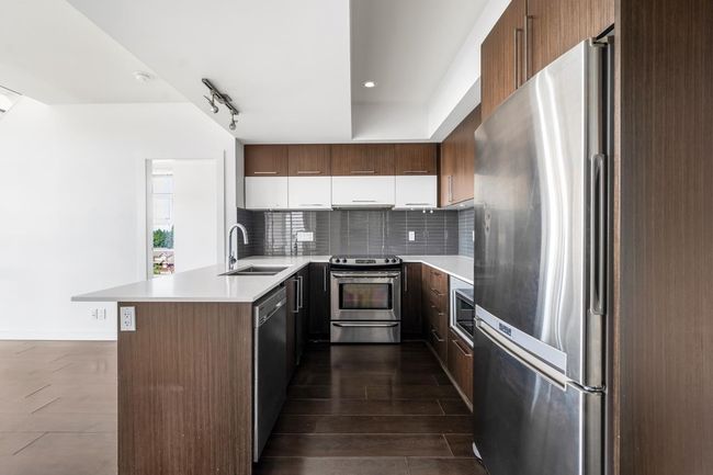 Kitchen with appliances with stainless steel finishes, a peninsula, backsplash, light countertops, and white cabinets | Image 10