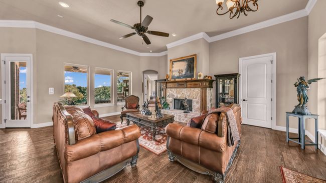 Living room featuring dark wood-style flooring, a stone fireplace, ceiling fan with notable chandelier, recessed lighting, and baseboards | Image 5
