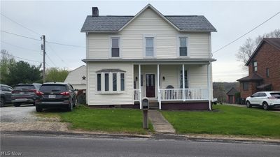 View of front of home with covered porch and a front lawn. | Image 1