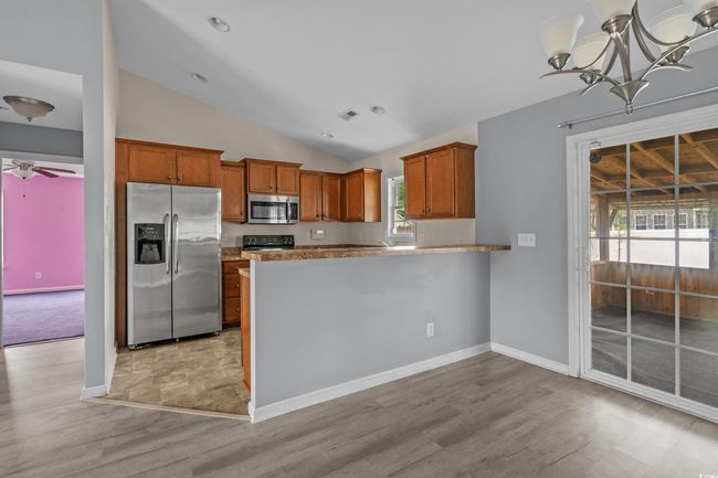 Kitchen with appliances with stainless steel finishes, vaulted ceiling, light wood-style flooring, and brown cabinetry | Image 18