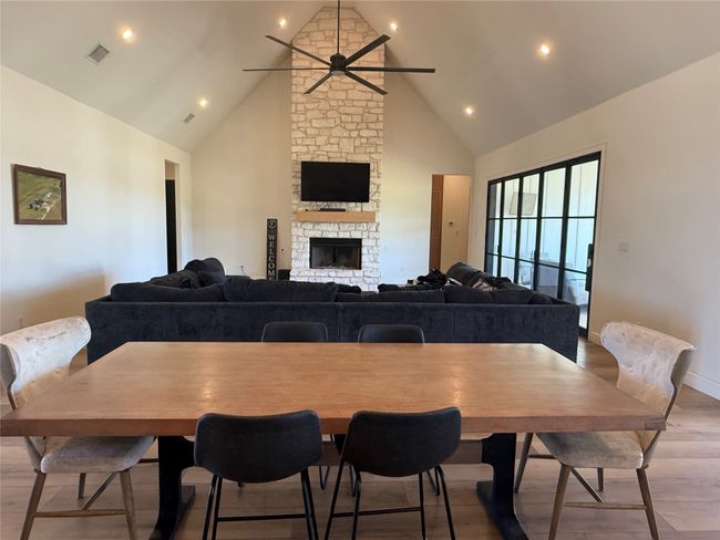 Dining room featuring light wood-style floors, a ceiling fan, high vaulted ceiling, a fireplace, and recessed lighting | Image 18